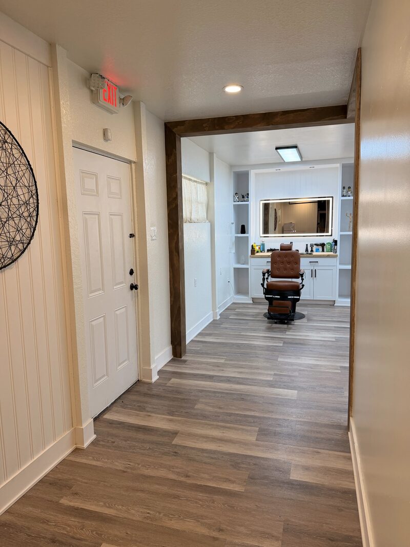 The entry hallway leading to a barber station framed by a dark wood beam