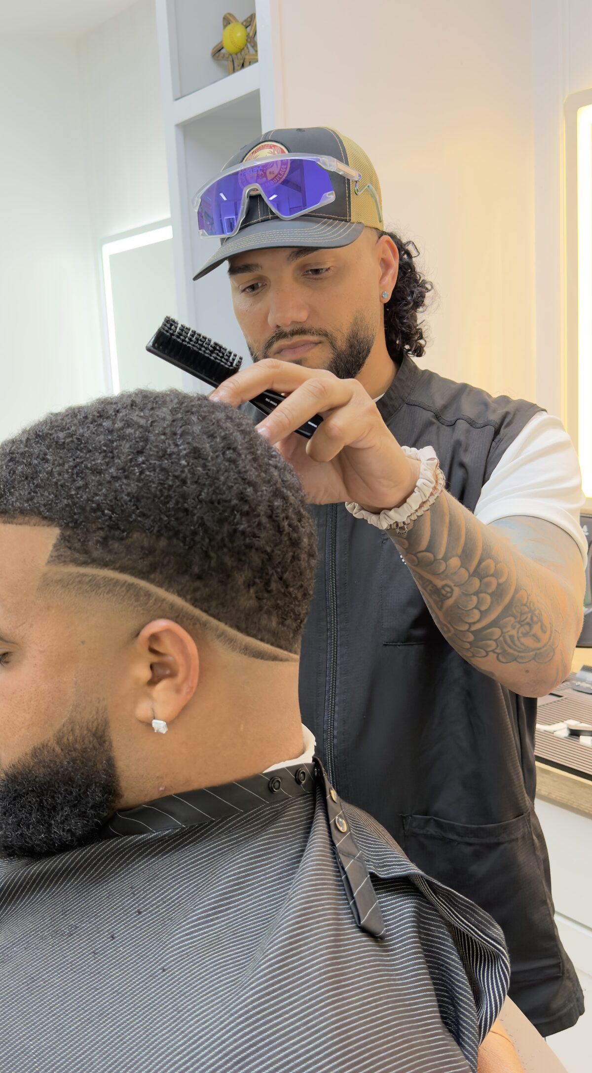A barber carefully styling a client's hair with a brush