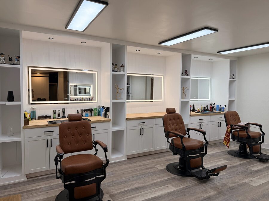 A row of camel leather barber chairs facing lit mirrors